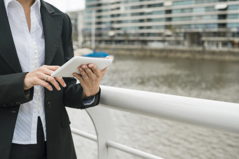 Mid section young woman standing near harbor using mobile phone